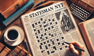 A crossword puzzle grid with a pen and scattered notes, featuring clues from the statesman NYT crossword.